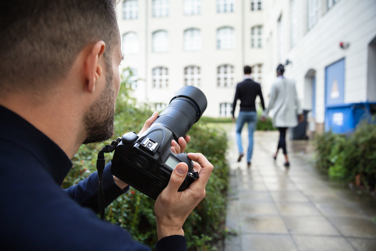Man Taking Photograph Of Couple Walking Together At Outdoors Young Man Paparazzi Photographer Capturing A Photo Suspiciously Of Couple Walking Together Using A Camera
